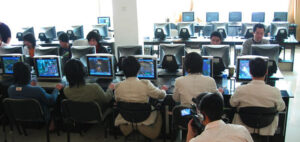 Chinese prisoners sit in front of rows of computers, goldfarming in World of Warcraft.