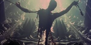 A tattered, impaled torso silhouetted by pale light against a biomechanical background in Event Horizon.