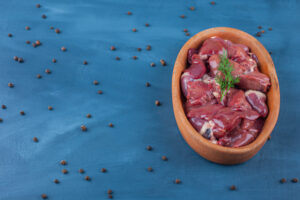 Uncooked offal in a bowl on a blue background.