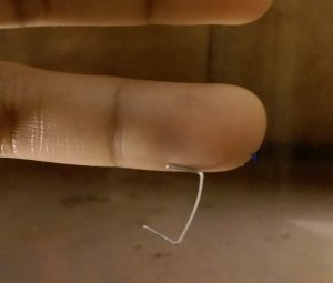 Staple magnetically clinging to a finger.