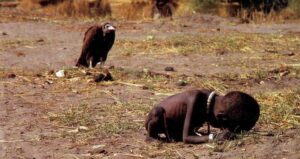 A vulture seems to stalk a starving child in the southern Sudanese hamlet of Ayod.